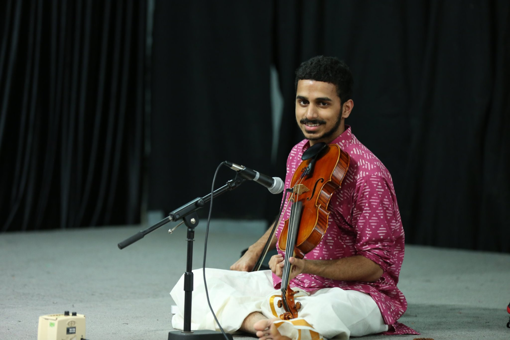 Achi Bala smiling during a Carnatic concert in a pink kurta